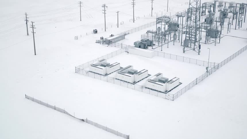 An aerial clip of a megapack battery covered with snow