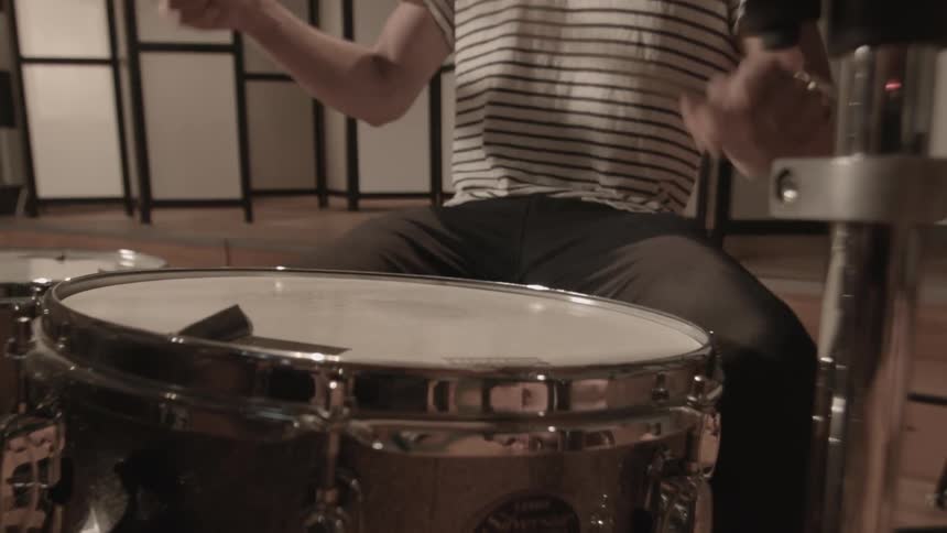 Closeup of a mans hands playing the drums indoors