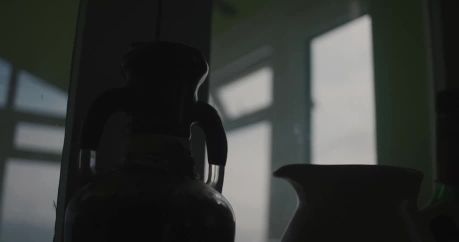 Two jugs sit next to a post inside a building