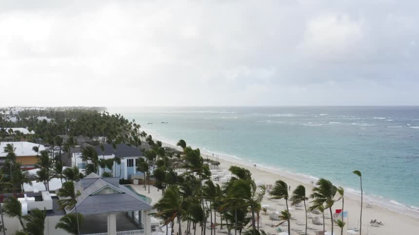 Aerial landscape of a tropical beach with palm trees houses and a sky with clouds