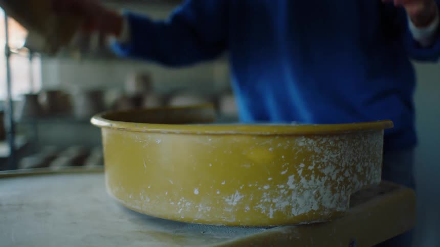 Female potter in pottery workshop puts outer cover onto potters wheel