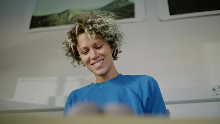 A lady smiling while looking down on something indoor
