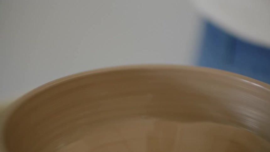 Female potter shapes clay bowl turning on pottery wheel