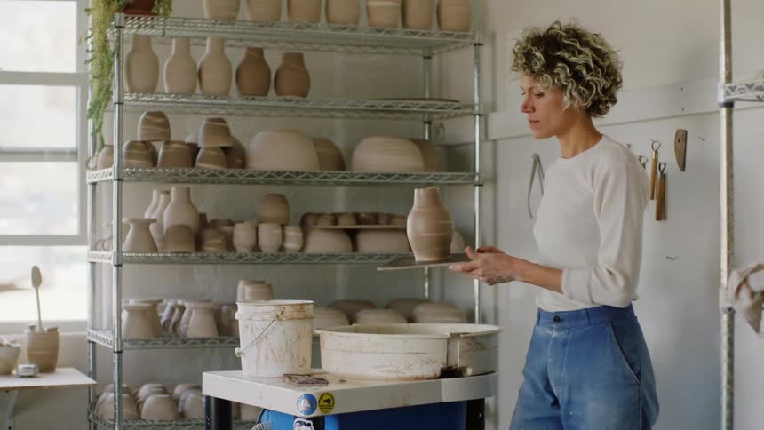 A woman sculpting a clay pot in an art room