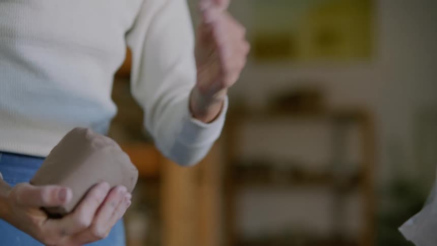 A white woman kneads a lump of clay
