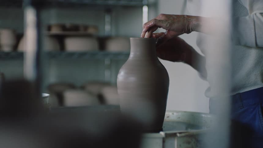 A female sculptor making a pot on the sculpting wheel at midday