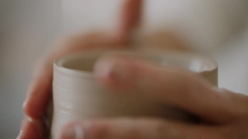 Womans hands modeling a clay vase