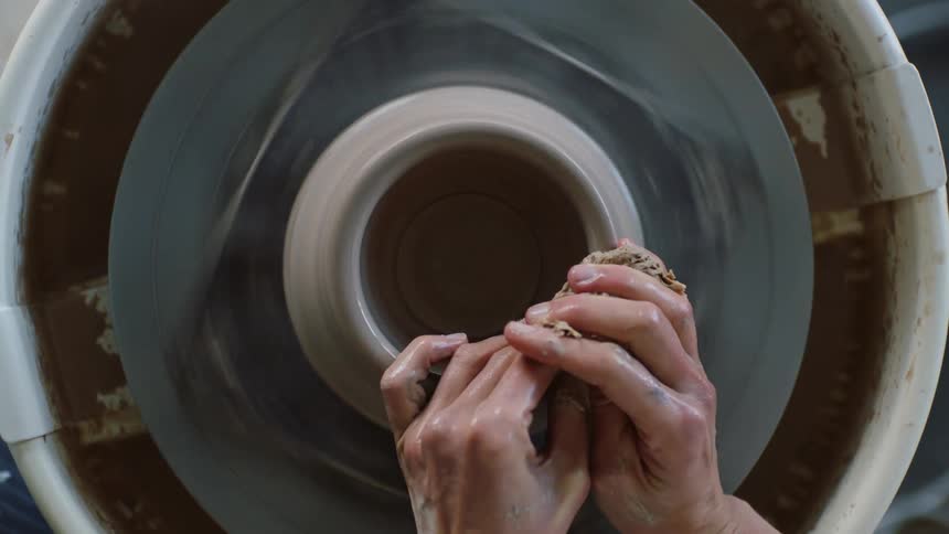 Persons hand discussing a clay vase