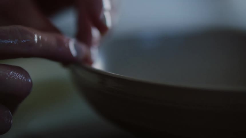 A person sculpting a clay bowl