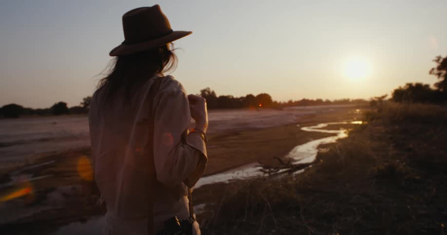 Lady on a hat walking at sunset while carrying a side bag