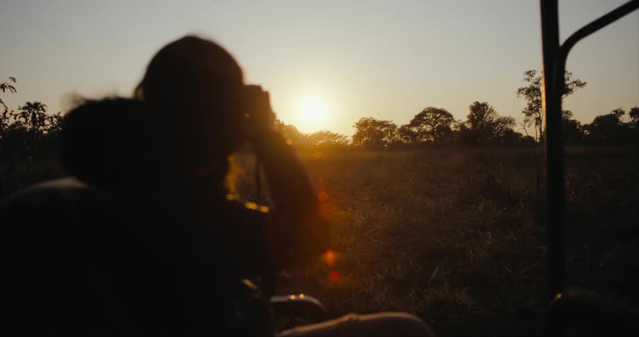 A person photographing the savanna during sunset