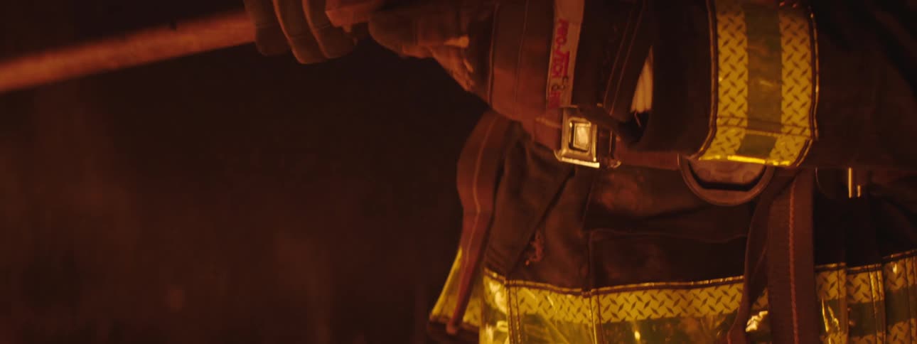 A fireman holding an axe while standing at night