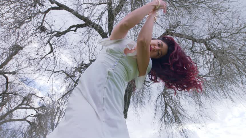 A woman is dancing under the tree