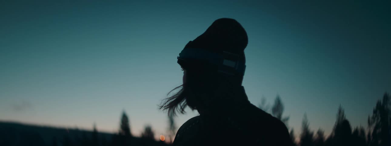 A silhouette of a person standing with a flashlight on their head in a darkening region