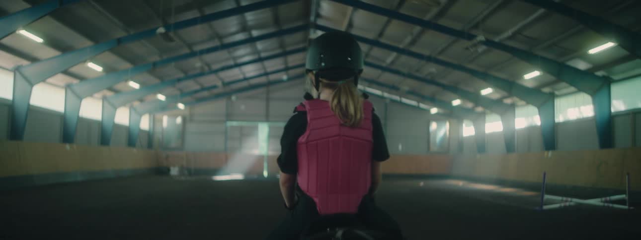 A girl rides a horse in the stables