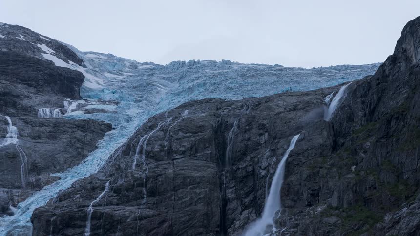 A waterfall of melted ice next to a glacier in the rocks
