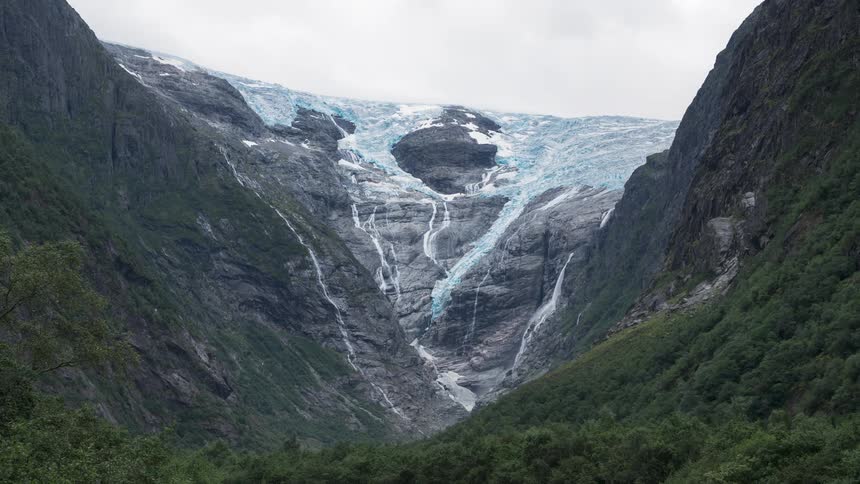 A waterfall from a glacier flows down the side of a mountain