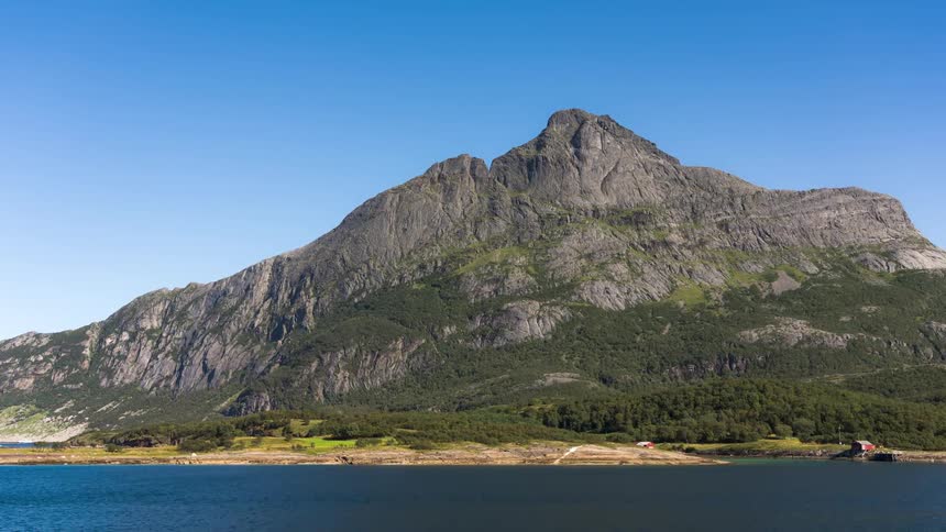 A time lapse landscape of a mountain and a lake under a clear sky