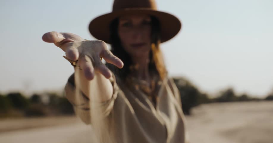 Woman with a handful of loose sand in an open environment