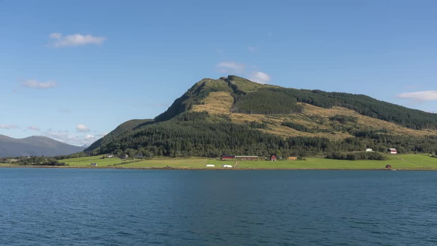 The camera moves across a body of water that is lined with a mountain range