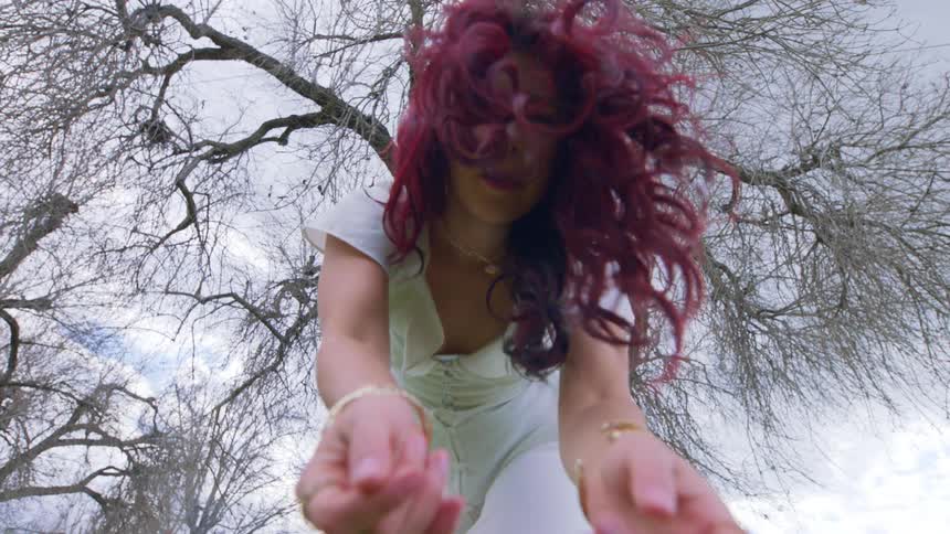 A young woman moves her body back and forth near trees