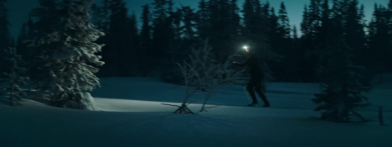 A person skiing in the snow at night with a flashlight
