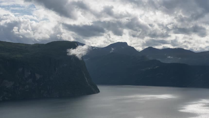 Clouds move over mountains and a lake