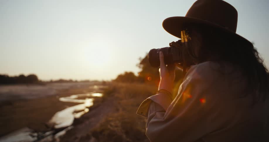 Photographer using a professional camera in a natural environment with the sky and the morning sun