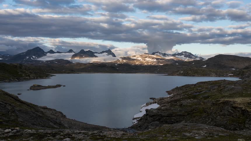 Landscape of a lake with mountains around with vegetation and snow