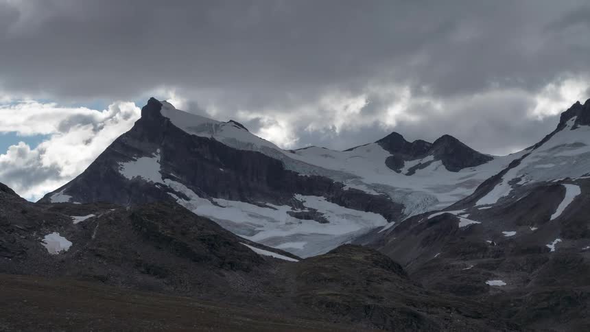 Clouds move over snow covered mountains