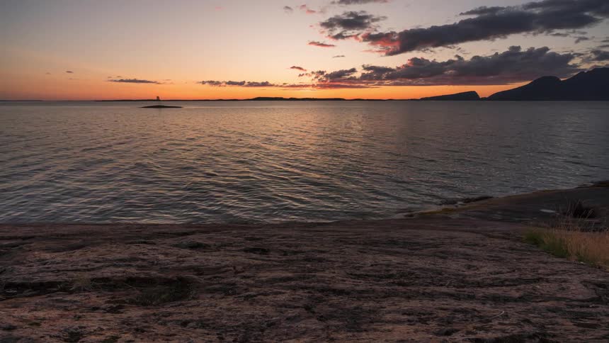 Lake landscape with silhouette of mountains around and the sunset on the horizon setting