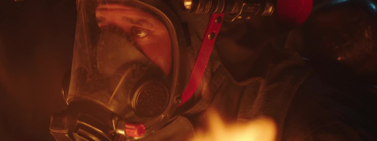 A fully equipped firefighter standing in front of burning flame
