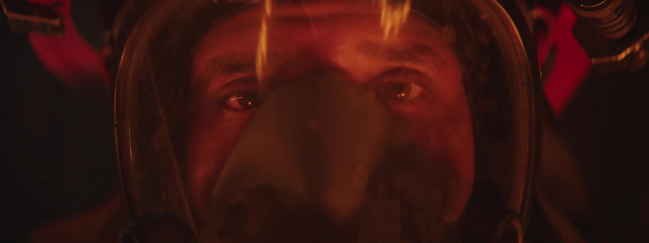 A scared firefighter opens his eyes as a fire reflects on his visor