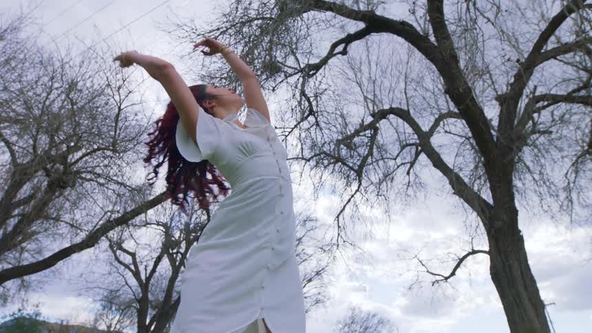 A woman is dancing by the tree