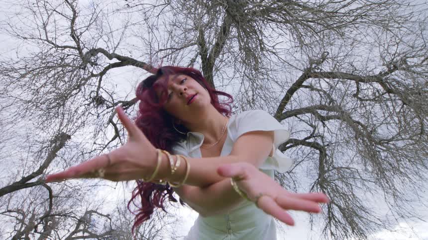 A young girl dances beneath a tree