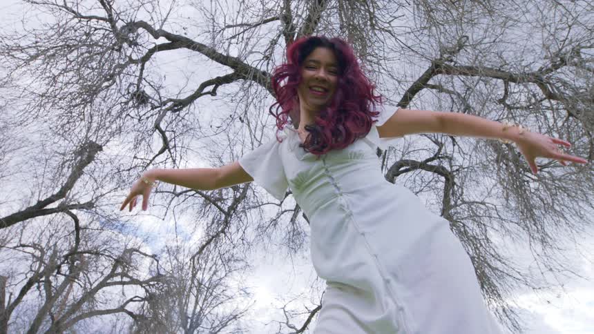 A young woman enjoys dancing in a forest