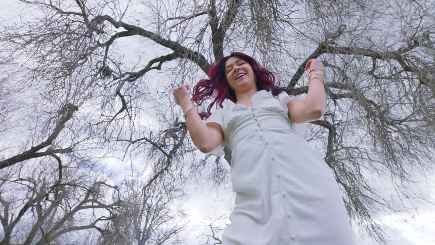 Happy woman with colorful long hair and white dress turns around smiling