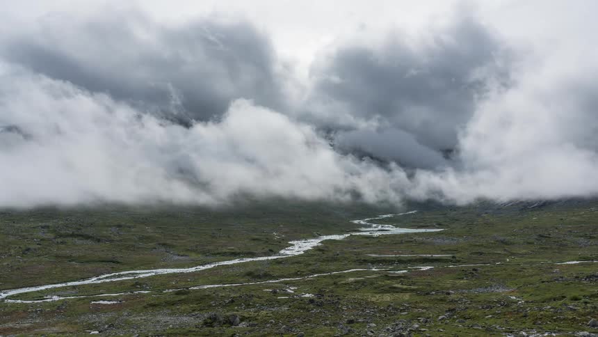 Clouds move over a landscape with a visible river