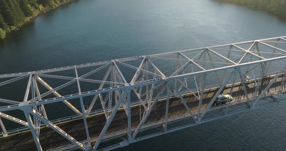Subtle pullback over a sunkissed bridge deck as a SUV drives through frame