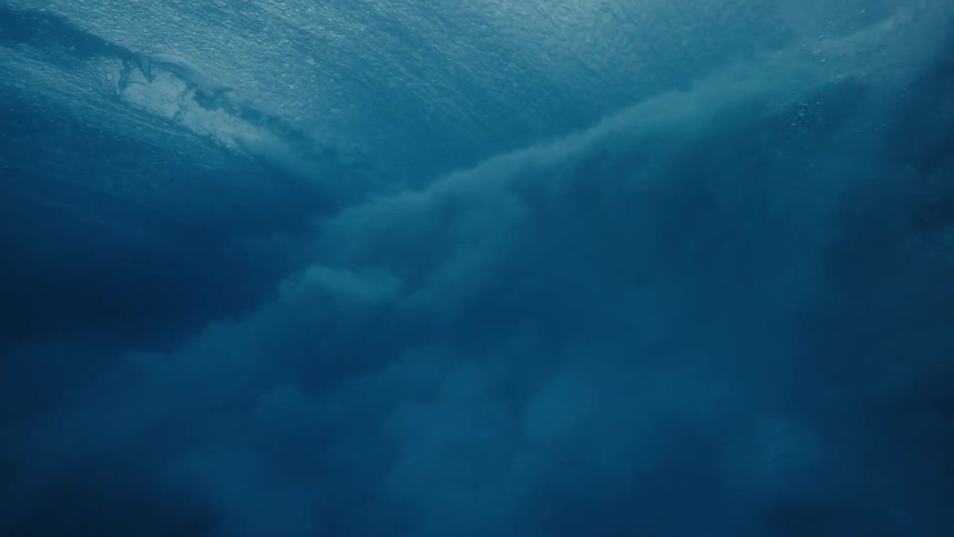 From beneath the oceans surface a wave is seen passing by