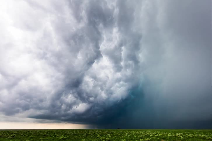 Dark clouds gather in the sky above the green field