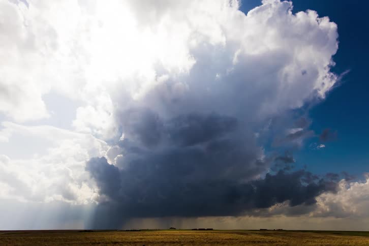 Sunbeams shining through the rain clouds over a flat terrain