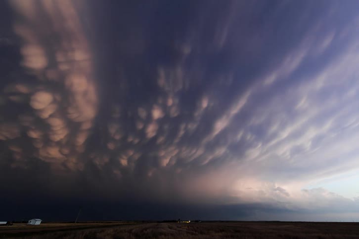 Dark clouds gather in the sky with mammatus and lightning strikes