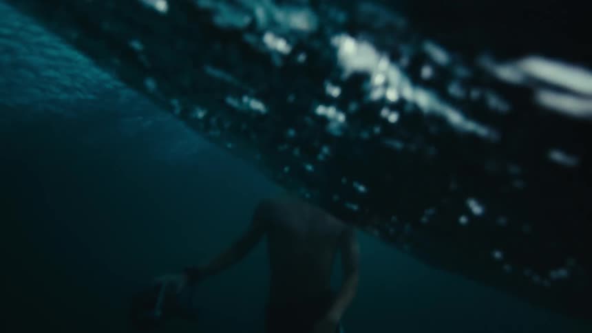 A male wearing goggles swimming in the ocean in waves
