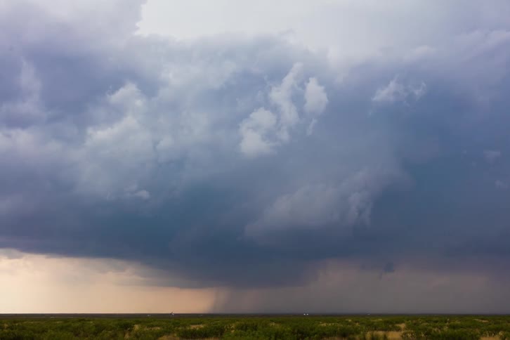 Dark storm clouds pour rain on rural land