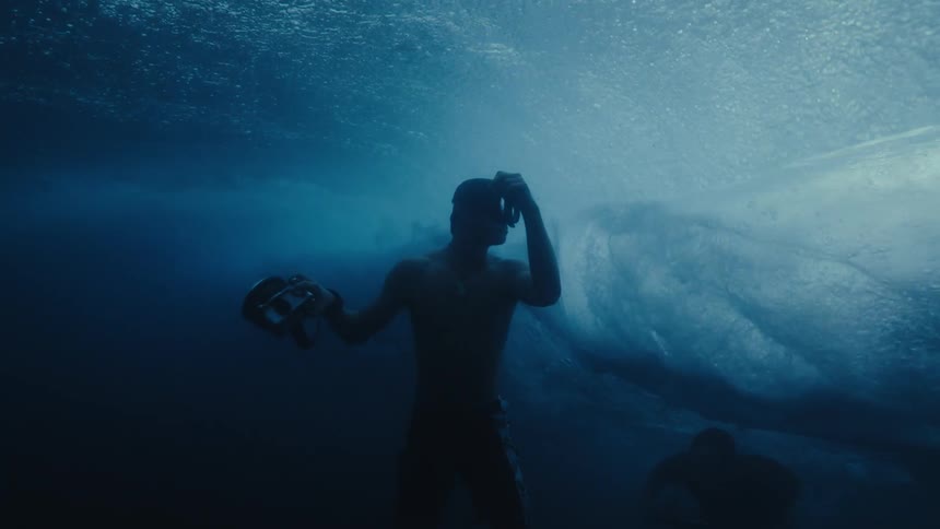 People with surfboards and cameras swiming under the ocean waves