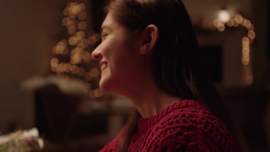 Woman sitting at table in room decorated for christmas laughs