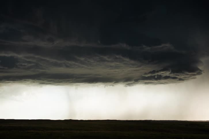 Dark storm clouds move in rotation as rain pours on the ground