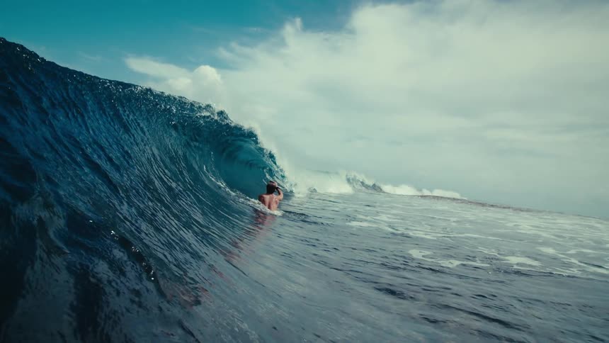 Man filming a wave breaking in the middle of the sea