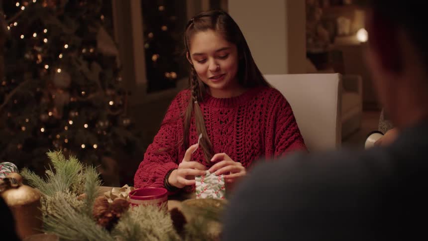 Female teen smiles after successfully wrapping a gift